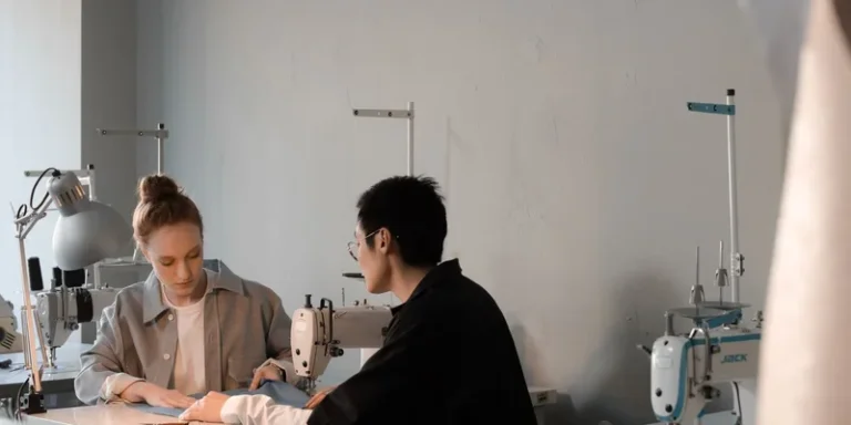 Two people working together in a sewing studio with machines and fabric