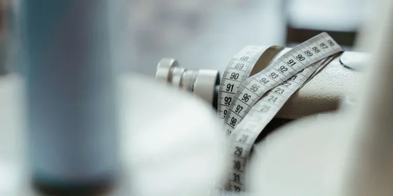 A sewing machine with a measuring tape draped over, emphasizing tailoring and craftsmanship
