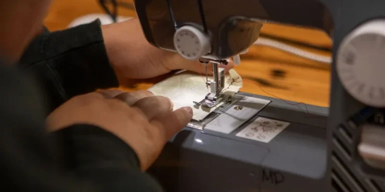 Hands sewing fabric with a sewing machine on a wooden table
