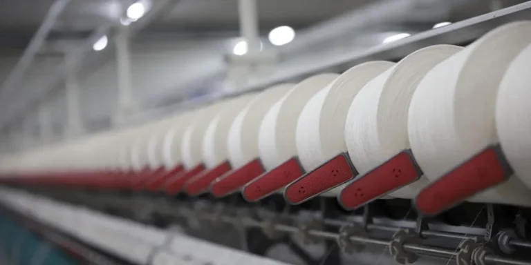 Close-up view of a textile production line showcasing white thread spools in an Indian factory