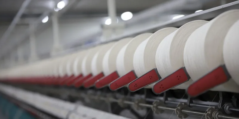 Close-up view of a textile production line showcasing white thread spools in an Indian factory