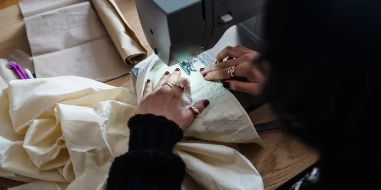 A close-up view of a seamstress working with a sewing machine, focusing on the fabric and hands
