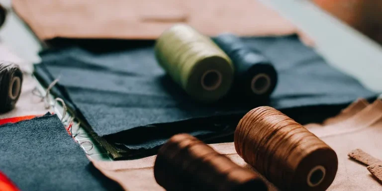 Vibrant spools of thread on various fabric pieces in a cozy workshop setting