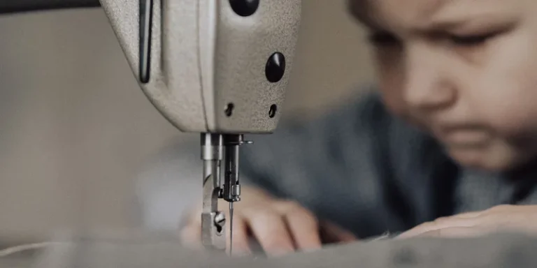 Close-up of a focused child using a sewing machine, emphasizing creativity and craftsmanship