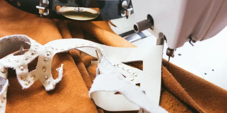Detailed view of a sewing machine stitching leather