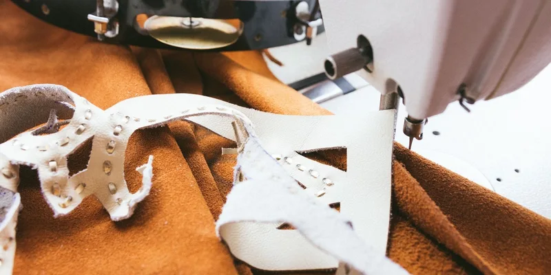 Detailed view of a sewing machine stitching leather