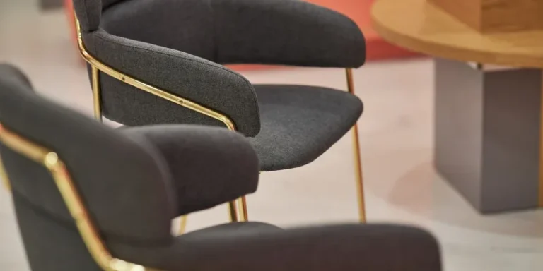 Close-up view of stylish gold-framed armchairs with gray upholstery in a contemporary office setting