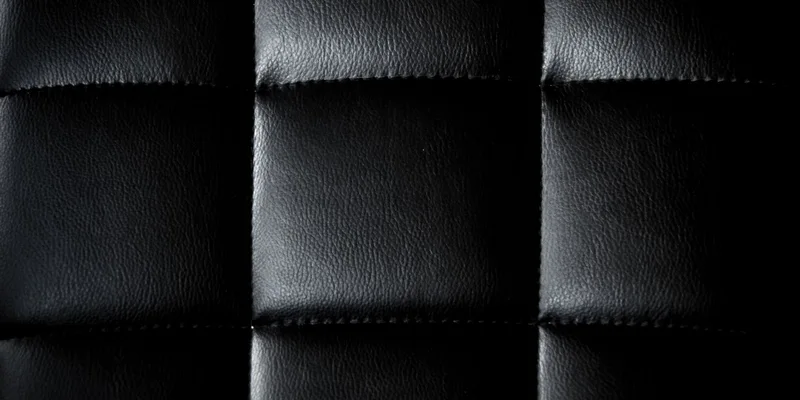 Detailed close-up of a black leather upholstery with a minimalist and modern texture