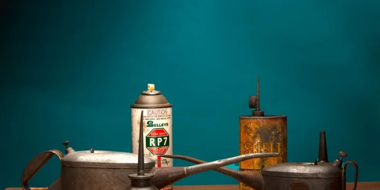 A collection of antique oil cans and vintage spray bottle against a green background in a studio
