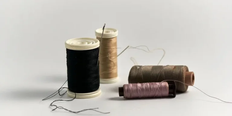Close-up of colorful sewing threads and needles on white background