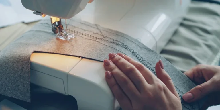 Hands guiding fabric through a sewing machine, stitching pattern