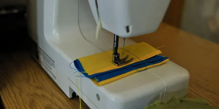 Sewing machine stitching colorful fabric layers on a wooden table
