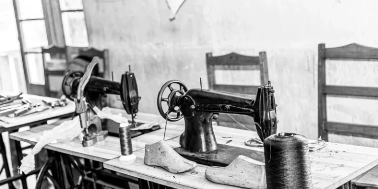 Black and white photo of a vintage sewing room with classic machines and spools