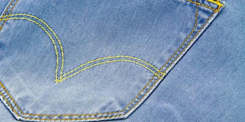 Detailed close-up of blue denim jeans pocket with yellow stitching
