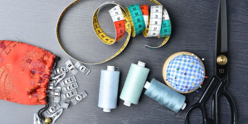 A vibrant arrangement of sewing tools including thread, tape measure, and scissors on a dark background